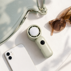 Folded compact handheld fan beside a handbag, phone and sunglasses