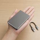Slim compact grey power bank shown in an adult hand with a separate USB-C cable