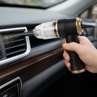 Cordless mini vacuum using a blower nozzle to clear dry dust from a car air vent