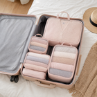 Blush pink packing cubes organising folded clothes inside an open suitcase