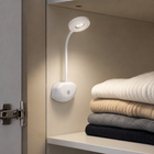 White rechargeable sensor light illuminating folded clothes inside a wardrobe
